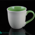 White trumpet shaped ceramic coffee cup with green handle